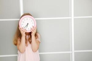 niña participación un reloj en su manos cubierta su cara con eso foto