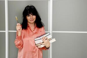 pretty senior woman with a stack of books and pencil in her hands photo