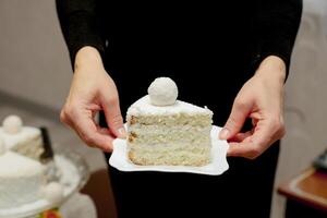 female hands holding a saucer in a large piece of cake photo