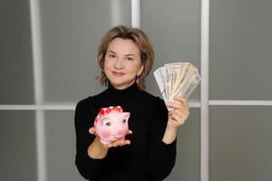 alegre mujer participación dinero y un cerdito banco en su manos foto