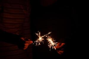 hand holding a sparkler at night during the festive season photo