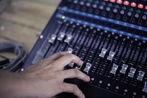 The DJ is adjusting the volume of the sound. Professional audio mixing console photo
