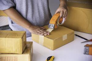 The staff is using the tape to pack the package goods to the customer. photo