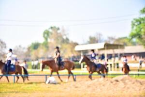 borroso imágenes de personas montando caballos en el práctica campo foto