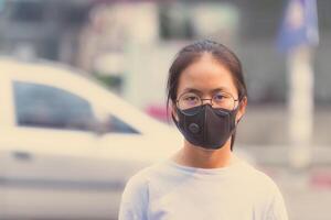 girl wearing a black noses N95 cloth to prevent dust pm 2.5 which has a very high value in a city with traffic photo