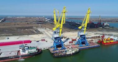 Aerial loading the Containers by crane , Trade Port , Shipping. Cranes for loading, unloading and sorting of containers. Container Cargo freight ship with working crane bridge in shipyard at dusk for video