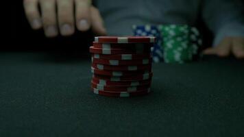 Poker chips and hands above it on green table. blackjack in a casino, a man makes a bet, and puts a chip. Stack of poker chips and two hands on green table. video