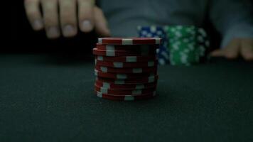 Poker chips and hands above it on green table. blackjack in a casino, a man makes a bet, and puts a chip. Stack of poker chips and two hands on green table. video