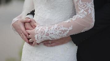 la mariée détient une mariage bouquet dans mains, le jeune marié câlins sa de derrière. jeune marié étreindre le la mariée de derrière video