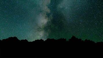 lechoso camino hora lapso hermosa noche cielo. hora lapso - hermosa lechoso camino galaxia encima montaña rango. noche cielo y estrellas, lapso de tiempo lechoso camino y resplandor encima árbol bosque, estrella y avión de línea caminos. video