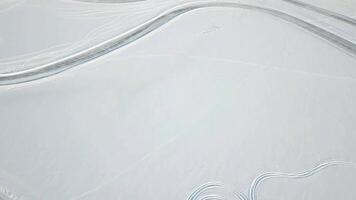 Winter landscape with tire trace on snow leaving to the horizon, sun and clouds in sky. Snow desert and the tracks of the car in the snow. Tracks on snow video