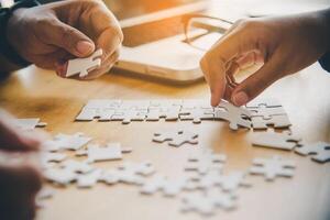 Business team handle a piece of white puzzles that are about to drop to get a complete worksheet - An attempt to succeed. photo