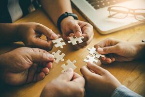 Business team handle a piece of white puzzles that are about to drop to get a complete worksheet - An attempt to succeed. photo