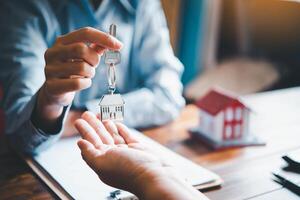 real estate agent gives the keys to the house buyer and signs the contract in the office. photo