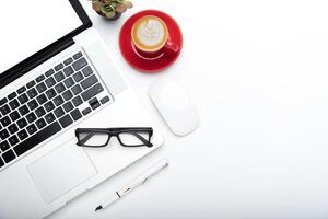 Top view with working desk with laptop,cellphone,notebook pencil coffee cup and eyeglasses in the office. photo