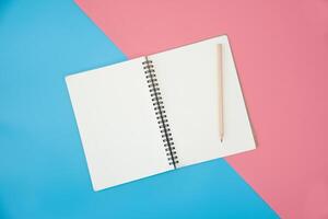 blank notebook with pencil on color background photo