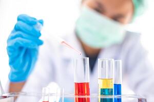 Female researchers are experimenting with pipette dropping a sample into a test tube in an experiment research in laboratory. photo