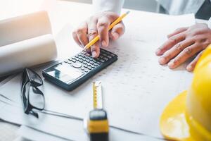 ingeniero trabajando en oficina con planos, inspección en lugar de trabajo para arquitectónico plan, construcción proyecto ,negocio construcción foto