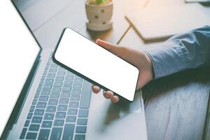 close-up mockup image of  hand holding black mobile phone with blank white  in desk work for home. photo