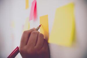 The hand is holding the post it notes attached to the wall. Concept brainstorming, share idea. photo