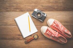 Travel accessories flatlay. Sneakers, notepad, watch, camera view from above. photo