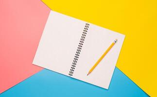 White notebooks and pencil laying on  color background photo