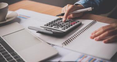 The accountant's hand is using the calculator. For cost analysis Profit and loss and tax calculation concept preparation of financial statements photo