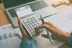 The accountant's hand is using the calculator. For cost analysis Profit and loss and tax calculation concept preparation of financial statements photo