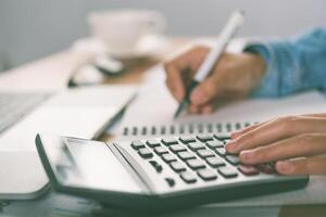 The accountant's hand is using the calculator. For cost analysis Profit and loss and tax calculation concept preparation of financial statements photo