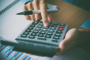 The accountant's hand is using the calculator. For cost analysis Profit and loss and tax calculation concept preparation of financial statements photo