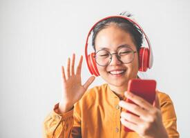 Asian teen in yellow dress talking on facetime video calling smartphone during the covid-19 coronavirus epidemic, social distancing, work from home new normal concept photo