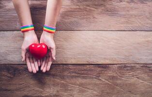 manos con un arco iris color pulsera metido en un de madera piso . gay derechos luchar. gay orgullo lgbt concepto foto