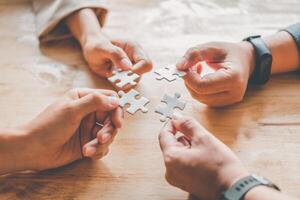 Business team handle a piece of white puzzles that are about to drop to get a complete worksheet - An attempt to succeed. photo