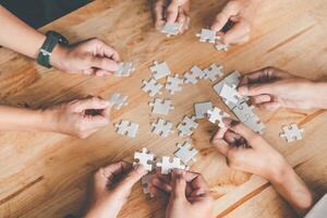 Business team handle a piece of white puzzles that are about to drop to get a complete worksheet - An attempt to succeed. photo