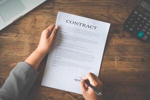 Hand holding pen signing contract in important documents. photo