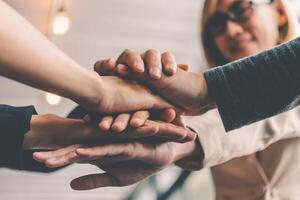 Hands of business people come together in a stack of hands to symbolize collaboration, teamwork to achieve goals and success. photo