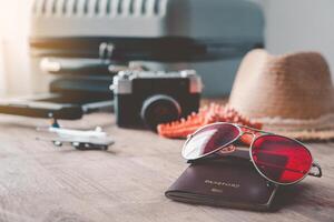 Passport placed on a wooden floor with a luggage and camera behind. Concept tourism planning and equipment needed for the trip photo