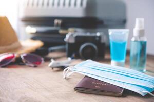 Passport placed on a wooden floor with a corona virus protection device Such as mask and gel mask with tourism equipment, concept tourism planning and new normal travel photo