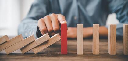 close-up hand The hand of a businessman who is stopping or preventing a falling block.Risk protection concept,Eliminating the risk photo