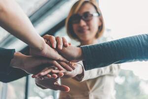 Hands of business people come together in a stack of hands to symbolize collaboration, teamwork to achieve goals and success. photo