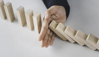 close-up hand The hand of a businessman who is stopping or preventing a falling block.Risk protection concept,Eliminating the risk photo