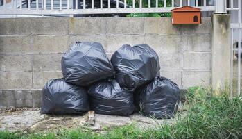 Garbage bags are stacked in front of the house, waiting to be collected by the garbage collector. photo