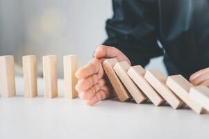 close-up hand The hand of a businessman who is stopping or preventing a falling block.Risk protection concept,Eliminating the risk photo