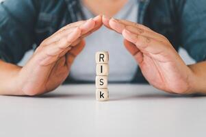 Hand protect wooden block with the word RISK Concept prevent risk. photo