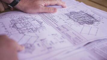 dichtbij omhoog visie Aan handen richten Bij technisch tekeningen aan het liegen Aan de tafel. Mens handen wijzend op sommige details in papieren, constructeurs Bij werk. video