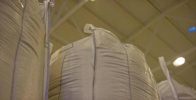 Warehouse for storage of fertilizers in bags. stack of big bag contain rice in warehouse. Big bags video