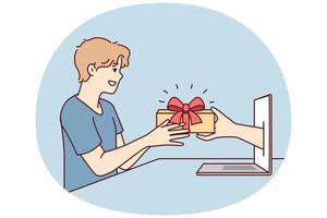 Young man receives present from hand poking out of laptop screen after online shopping. Vector image