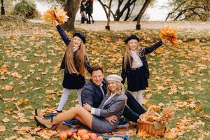 un grande familia en un picnic en el otoño en un naturaleza parque. contento personas en el otoño parque foto