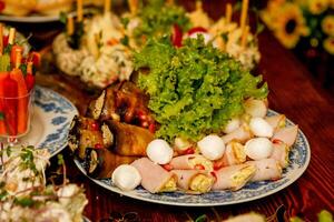 plate with appetizers of eggplant, ham, lettuce with cheese on the table photo