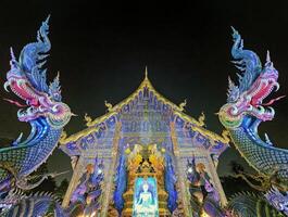 viharn y dragones a wat rong suea diez azul templo por noche, chiang rai, Tailandia foto